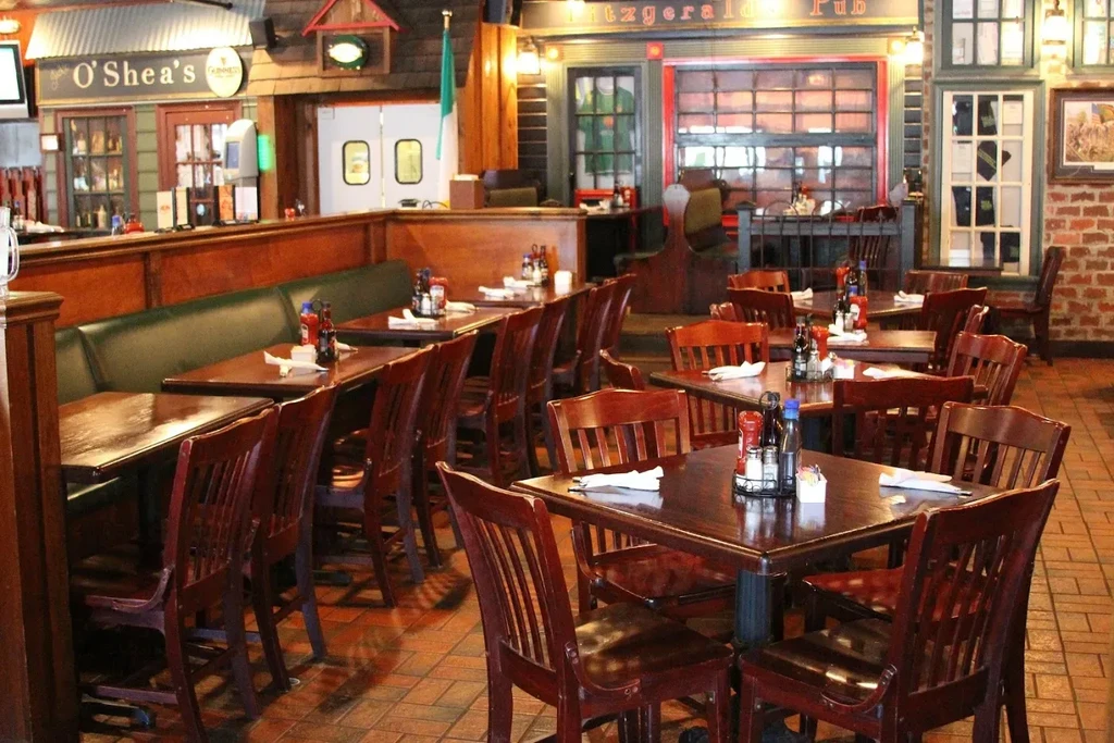 Warmly lit, empty Irish pub interior with set tables and a bar.