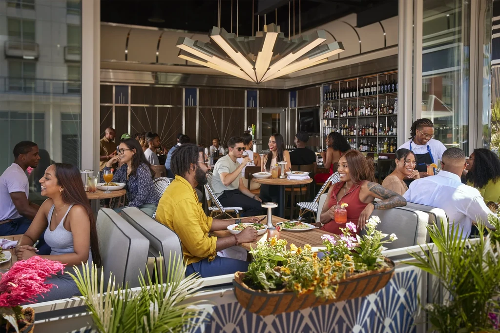 Modern outdoor restaurant bar filled with socializing patrons.
