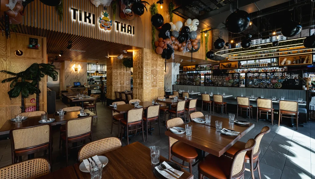 Vibrant Tiki Thai restaurant interior with carved pillars and themed decor.