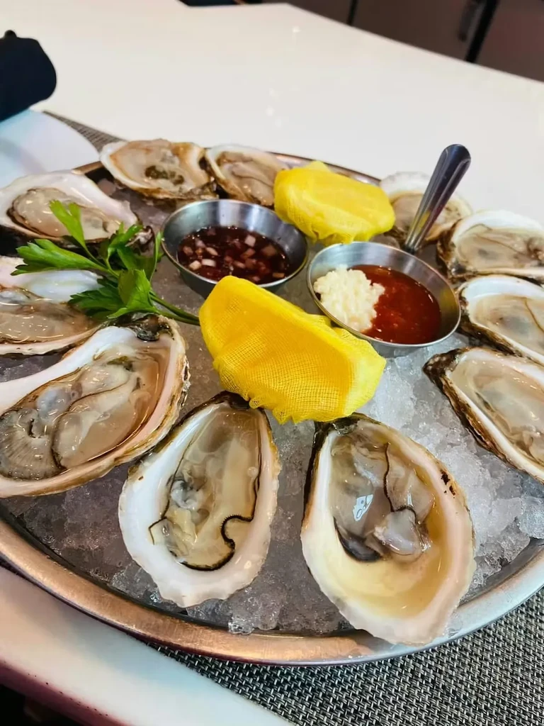 Fresh shucked oysters on ice with sauces, lemon, and parsley.