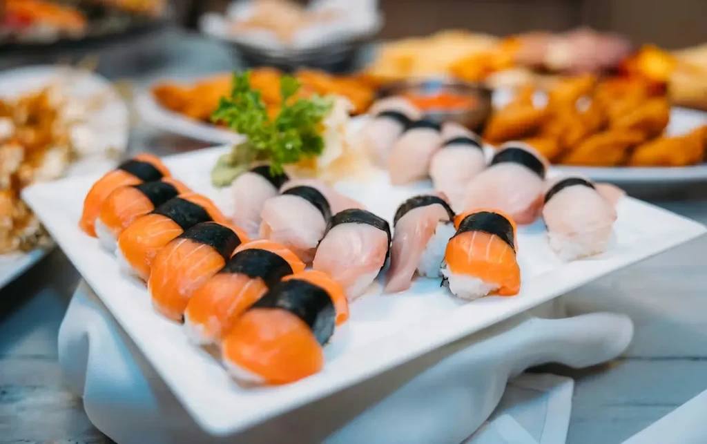 Platter of salmon and white fish nigiri sushi with garnishes.