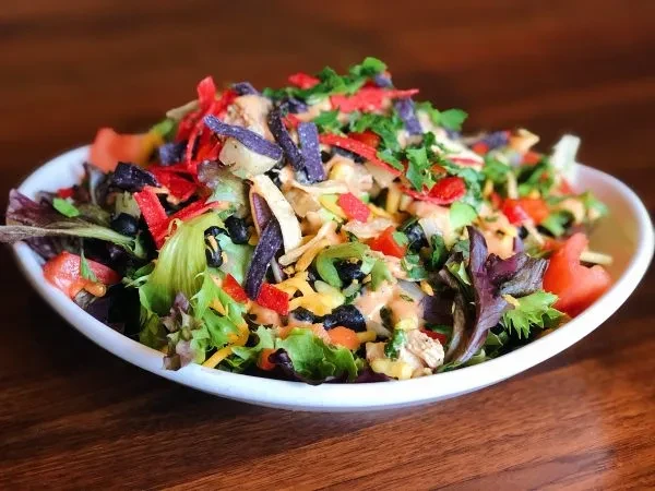 Vibrant Southwestern salad with chicken, beans, cheese, and tortilla strips.