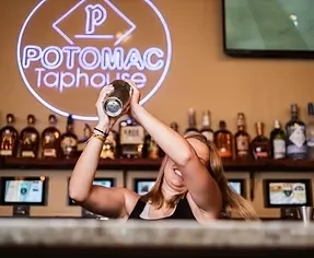 A blonde bartender shakes a cocktail at Potomac Taphouse.