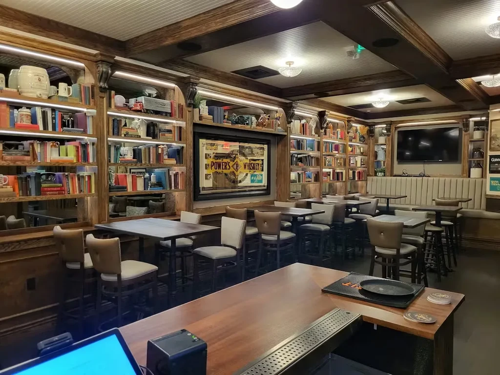 Empty, cozy library-style pub with wooden bookshelves and bar.