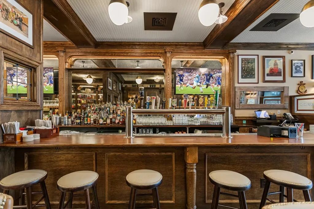 Traditional bar interior with liquor, beer taps, and soccer on televisions.