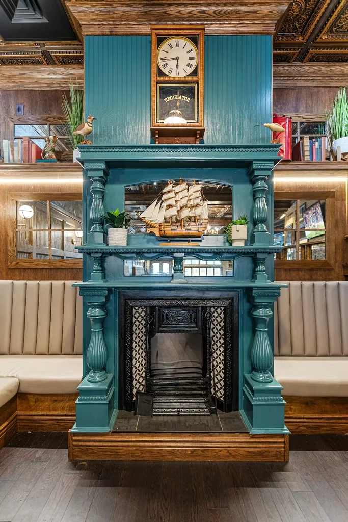 Ornate teal fireplace with sailing ship model in a traditional interior.