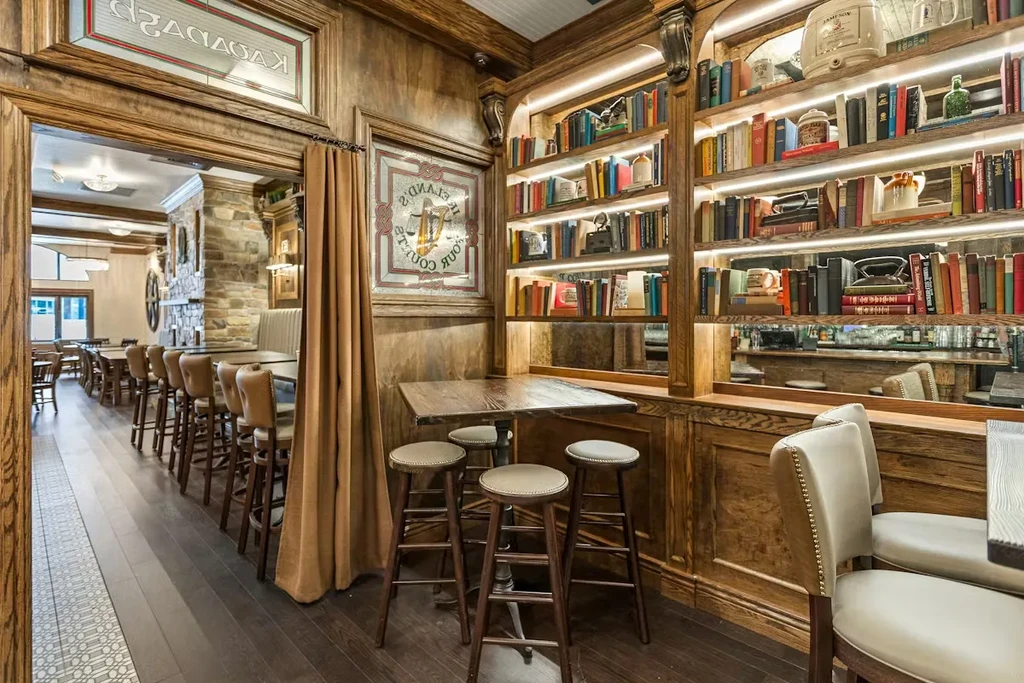 Sophisticated library-themed bar interior with a dark wood bookshelf.