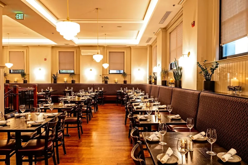 Empty, elegantly set restaurant dining room with warm lighting.