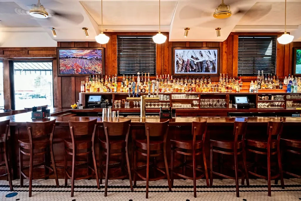 A well-lit dark wood restaurant bar with stocked spirits and taps.