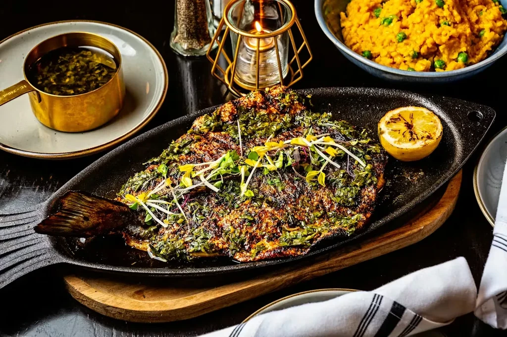 Grilled fish with herbs, lemon, and rice on a fish-shaped platter.