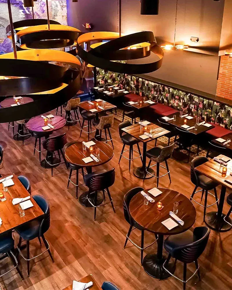 Restaurant interior featuring high-top tables, banquettes, and spiral light fixtures.
