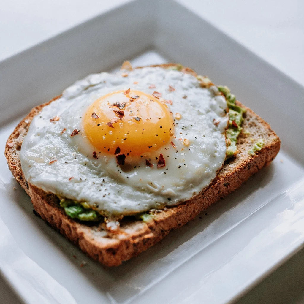 Whole-grain toast topped with mashed avocado, fried egg, pepper, and chili flakes.