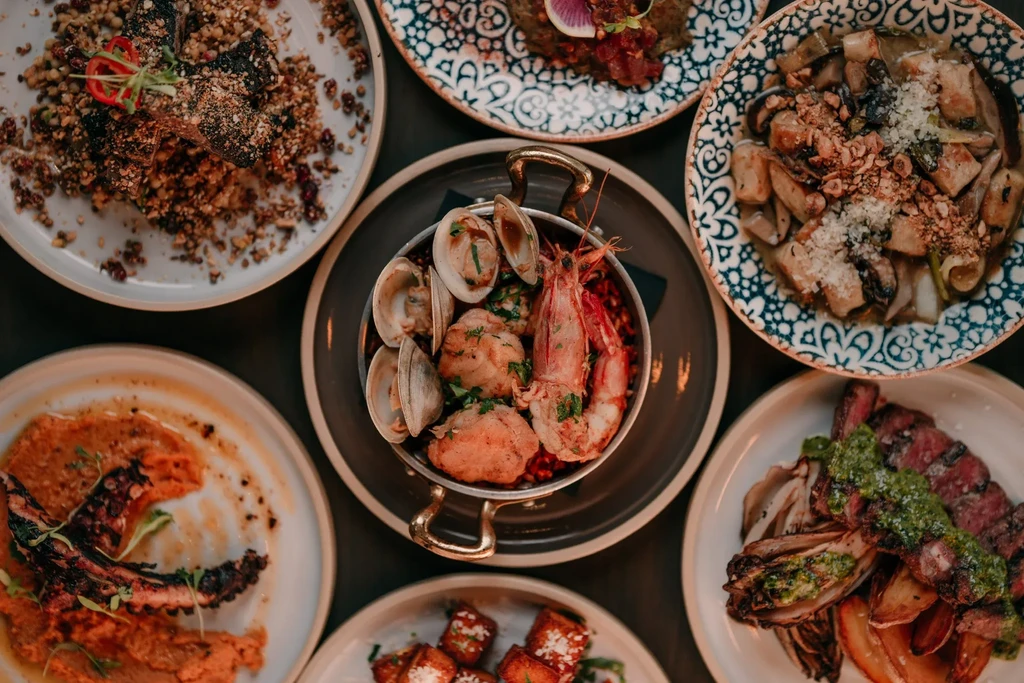Overhead shot of many exquisitely plated gourmet dishes on a dark table.