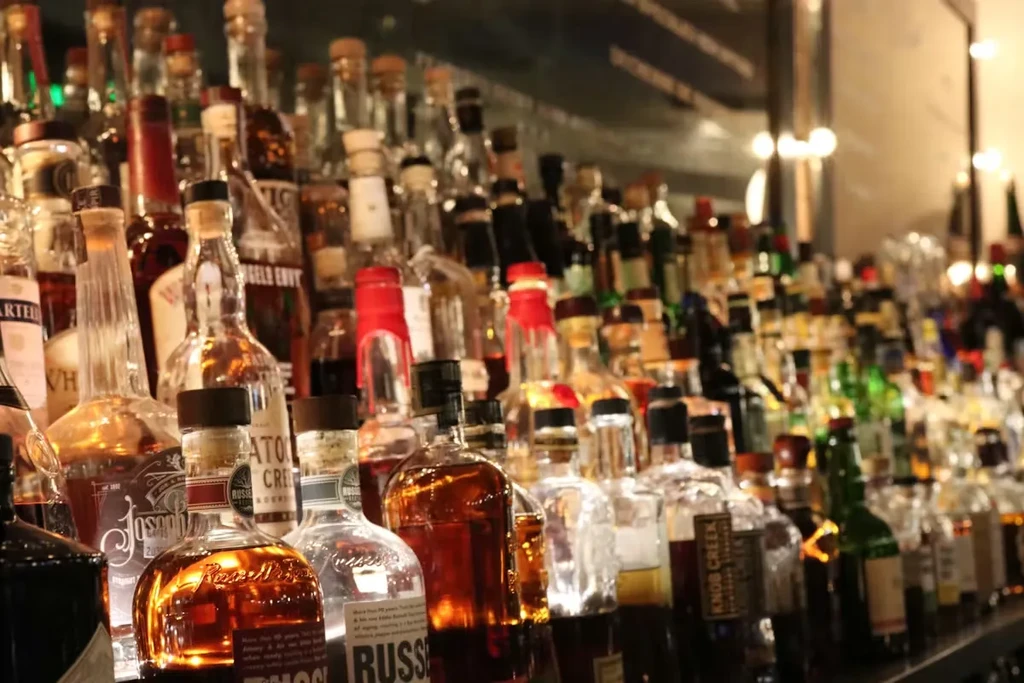 Numerous bottles of whiskey and bourbon on well-lit bar shelves.