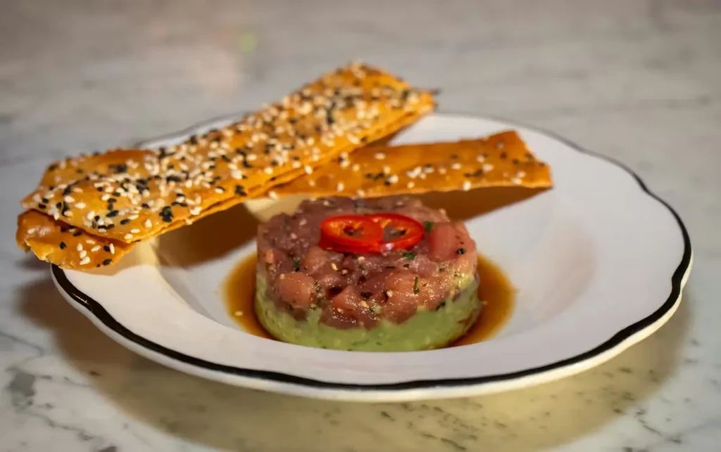 Tuna tartare over avocado, topped with chili, served with sesame crackers.