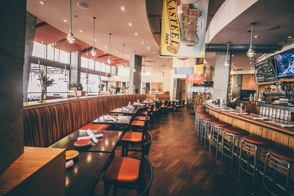 Empty modern restaurant interior with a bar, booths, and a fireplace.
