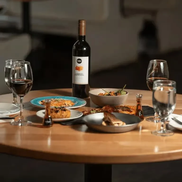 Elevated view of a dinner table with red wine, dishes, and drinks.