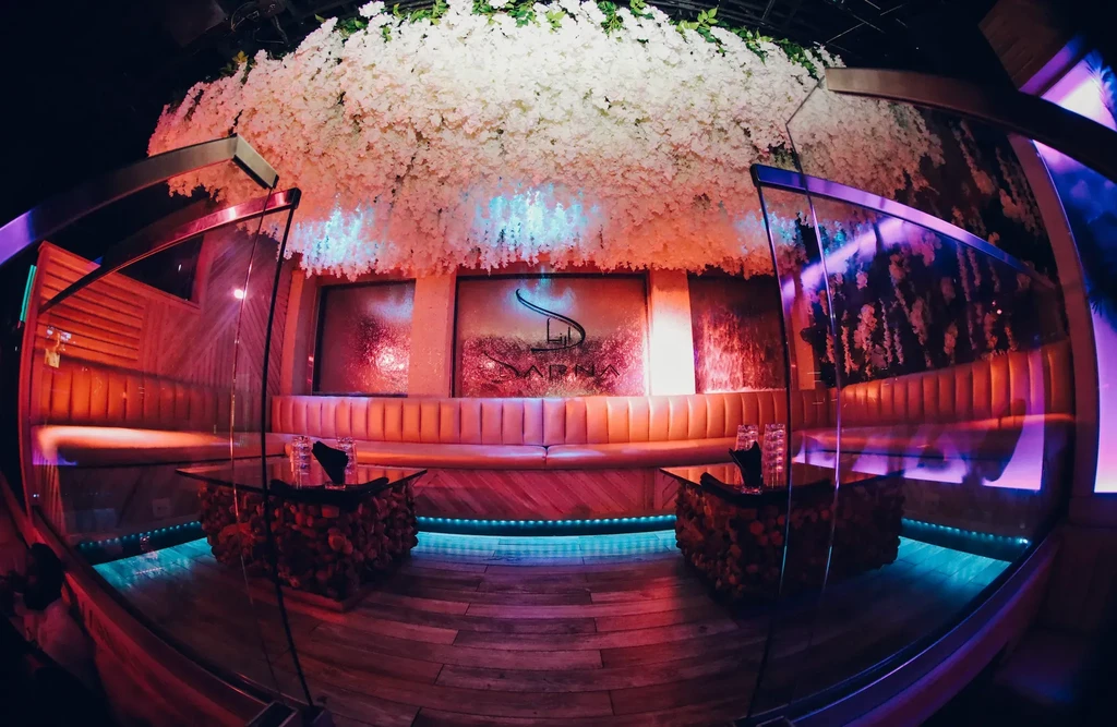Sarna restaurant: floral ceiling, tufted booths, and dramatic red/teal lighting.