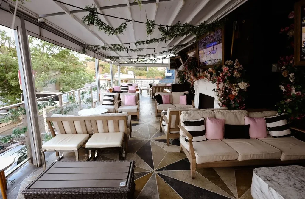 Stylish, empty outdoor patio with diverse seating, string lights, and floral mantel.