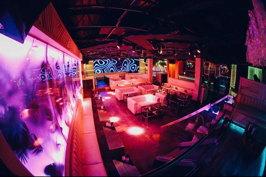 Purple neon lights illuminate a modern lounge bar with open seating.