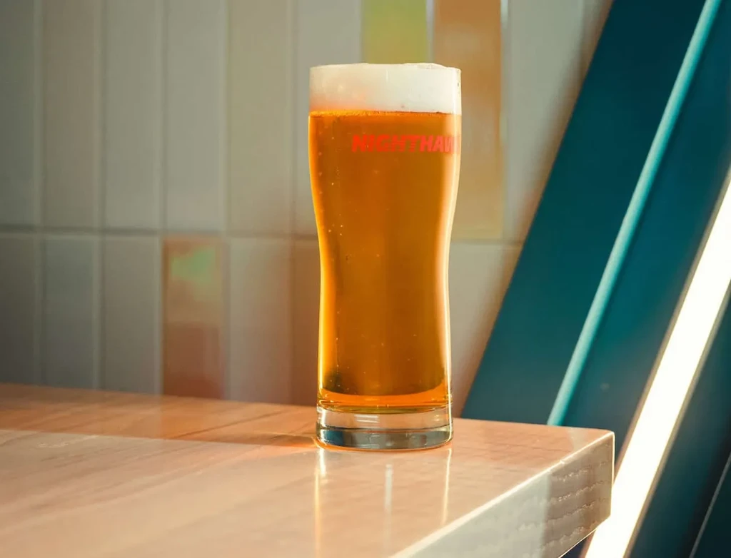 NIGHTHAWK golden-amber beer in a glass on a modern countertop.