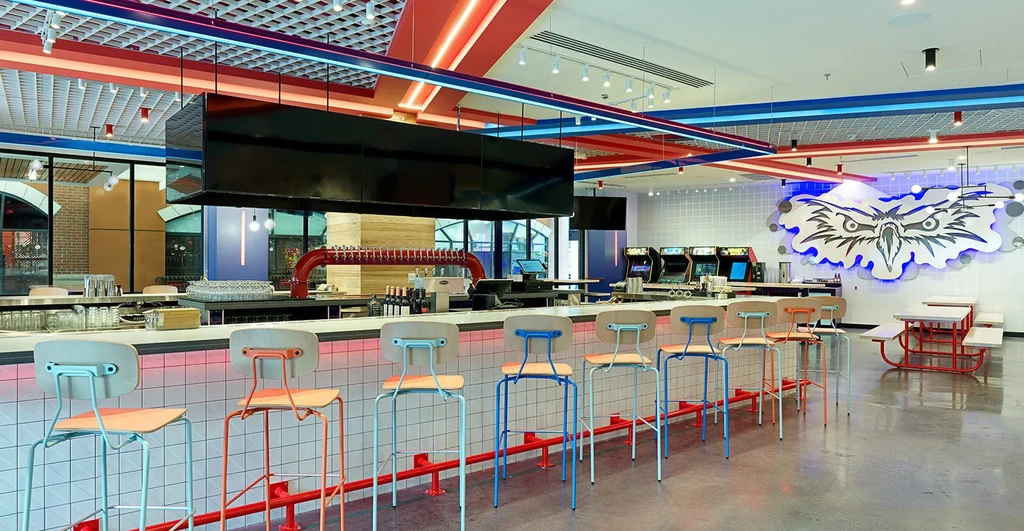 Vibrant retro bar with colorful stools, beer taps, and eagle art.