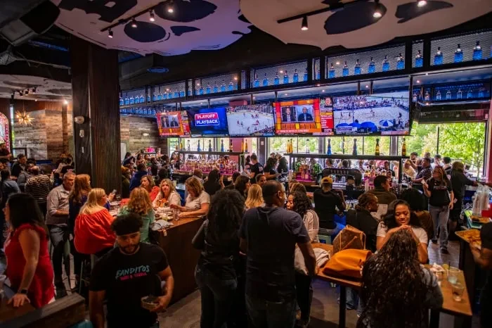 Lively sports bar interior with a diverse crowd and multiple TVs.