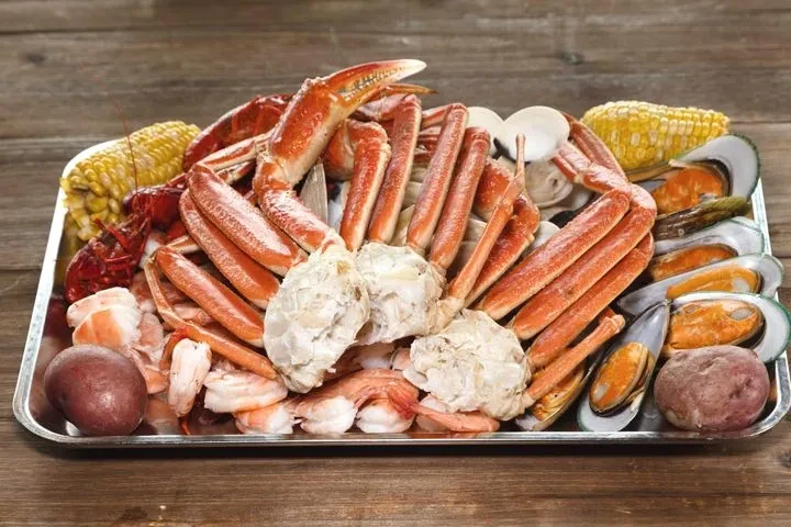 Large cooked seafood platter with crab, lobster, shrimp, mussels, and vegetables.