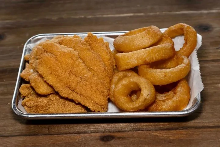 Fried fish fillets and onion rings on a paper-lined metal tray.