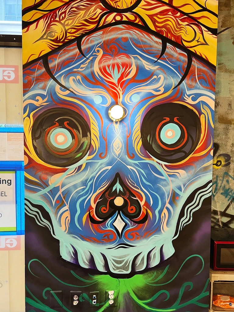 Vibrant sugar skull mural with a glowing circular light.