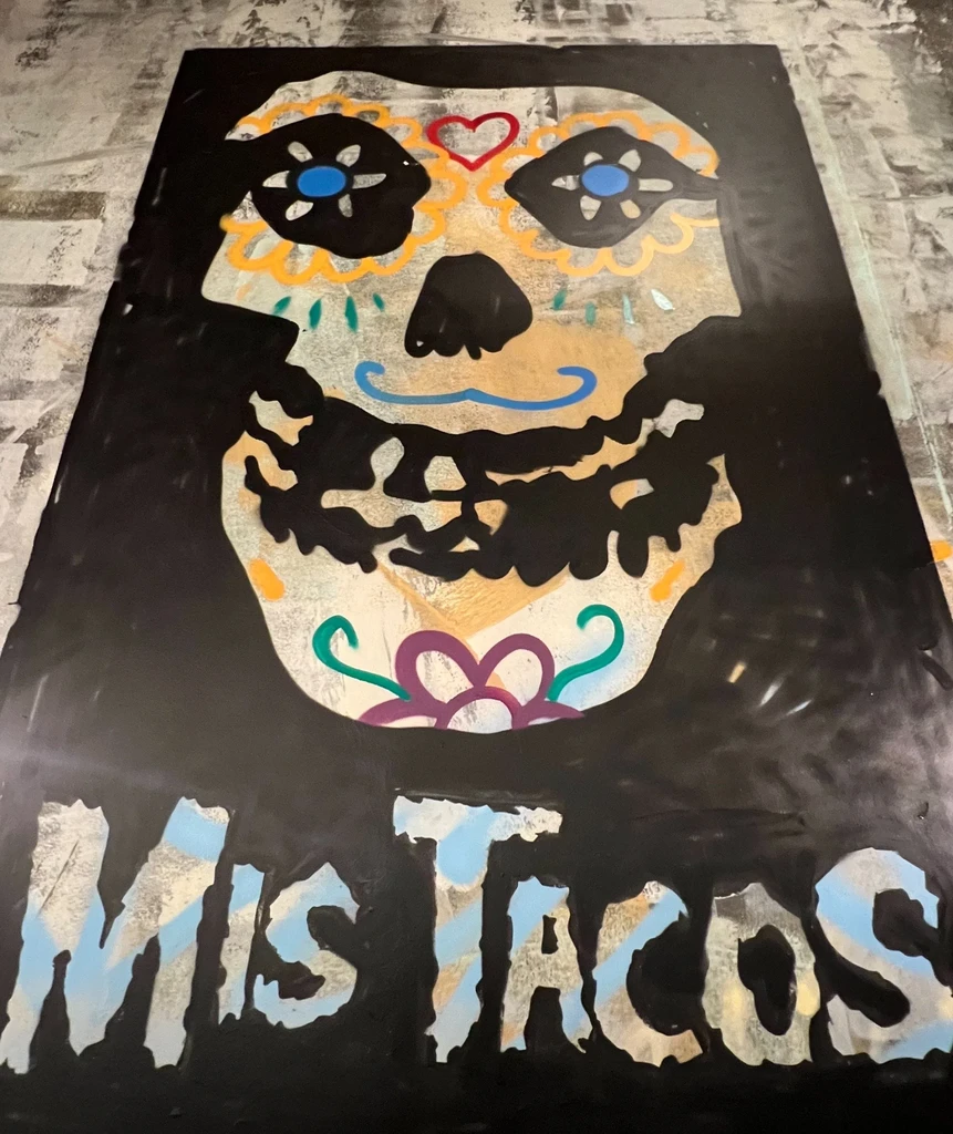 Day of the Dead sugar skull artwork with 'MIS TACOS' text on black.