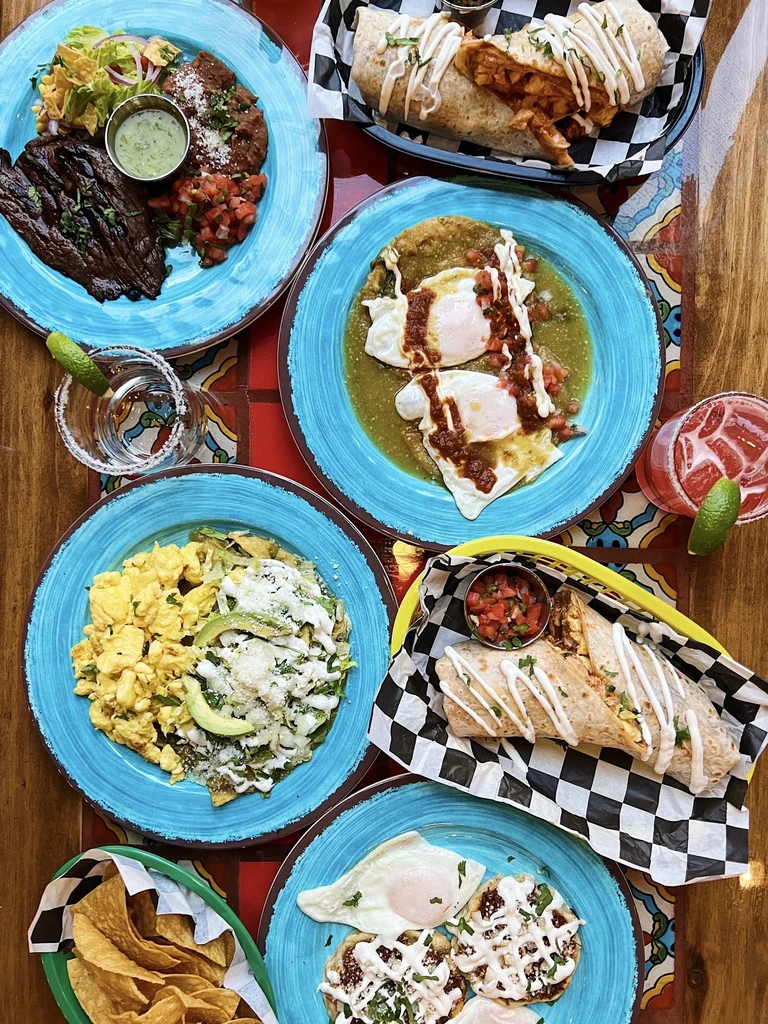 Vibrant Mexican and Tex-Mex food and drinks on a wooden table.
