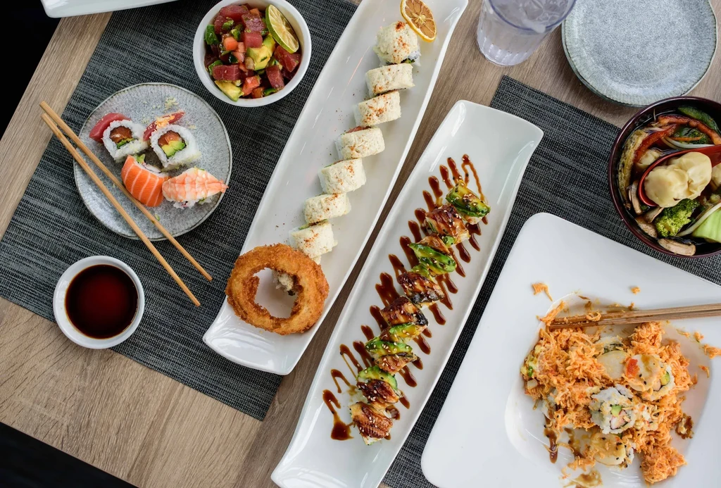 Assortment of Japanese sushi, poke, and other dishes on a wooden table.