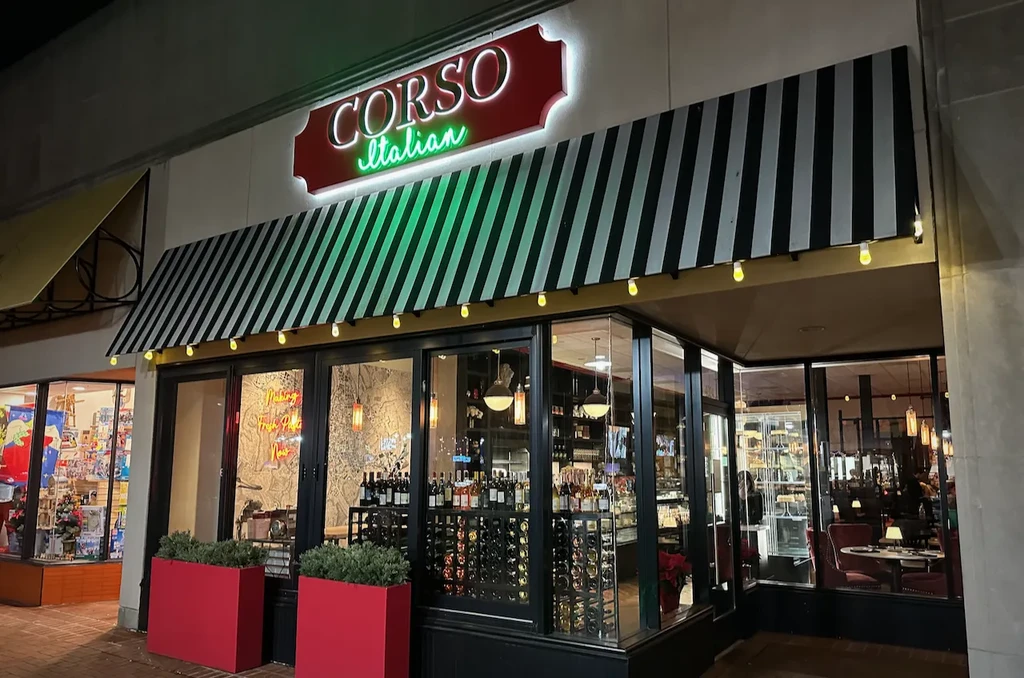 CORSO Italian restaurant exterior at night with neon sign and warm lighting.