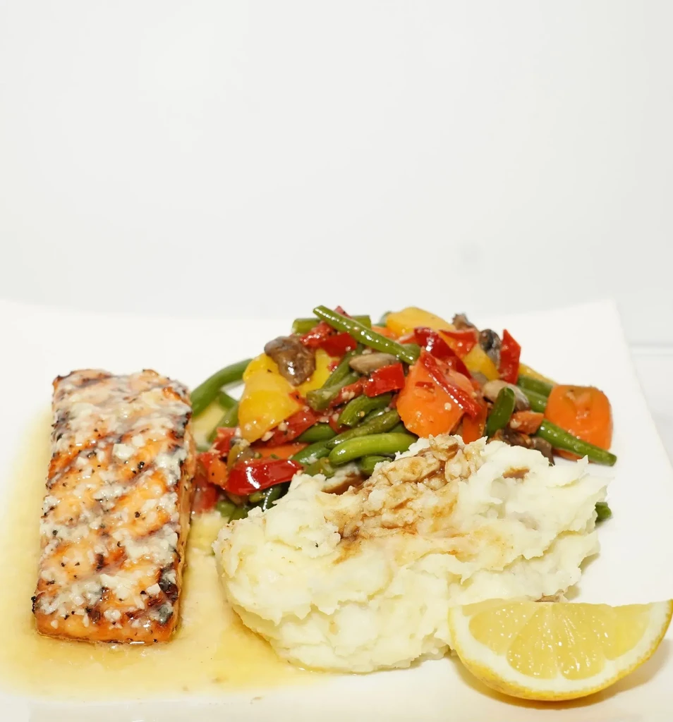 Grilled salmon, mashed potatoes, mixed vegetables, and lemon wedge.