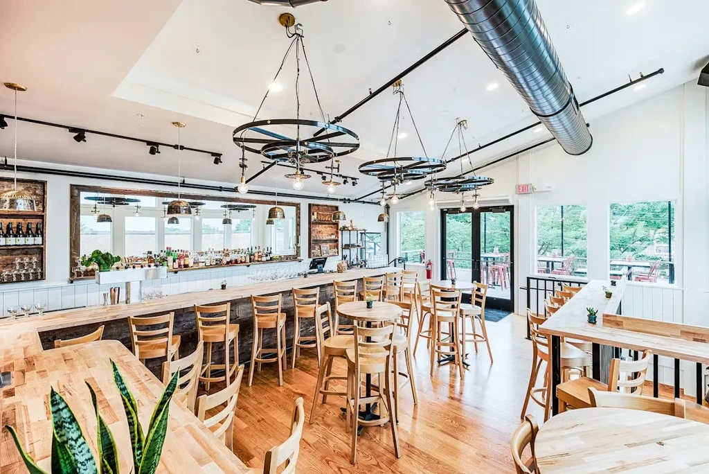 Bright, empty restaurant interior featuring a bar, industrial decor, and patio view.