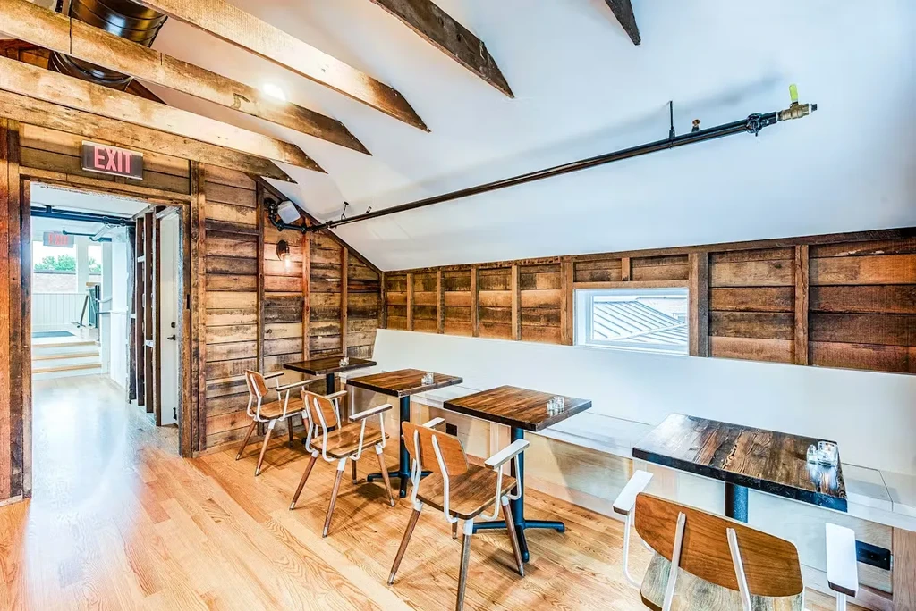 Empty rustic dining area with wooden walls, beams, and modern tables.