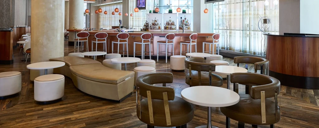 Modern restaurant lounge with diverse seating, copper bar, and warm lighting.