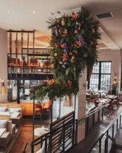 Multi-level restaurant interior with a large cascading floral ceiling arrangement.
