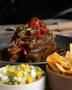 Braised meat with roasted peppers, microgreens, salsa, and tortilla chips.