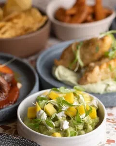 Three restaurant dishes: green dip with mango, fried fish, and meat.