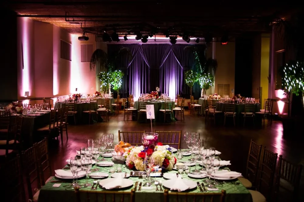 Elegant banquet hall with green and gold tables set for an event.