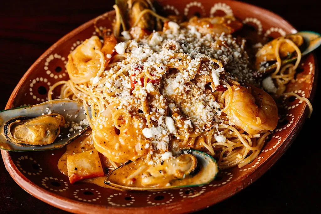 Shrimp and mussel pasta in creamy sauce on clay plate