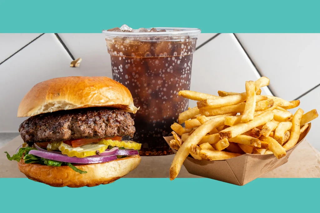 Well-lit close-up of a cheeseburger, golden french fries, and soda.