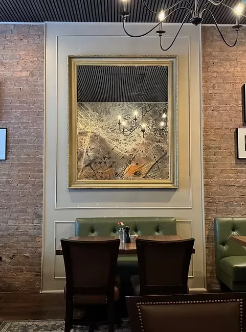 Elegant, warmly lit restaurant interior with golden mirror and green booth.