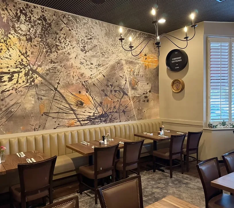 Interior of a restaurant with a beige booth and abstract grey-gold mural.