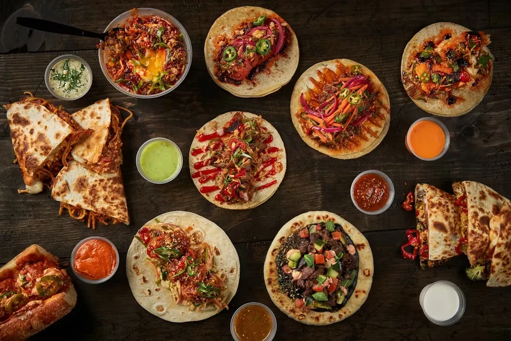 Overhead shot of colorful Mexican tacos, quesadillas, rice, and sauces.