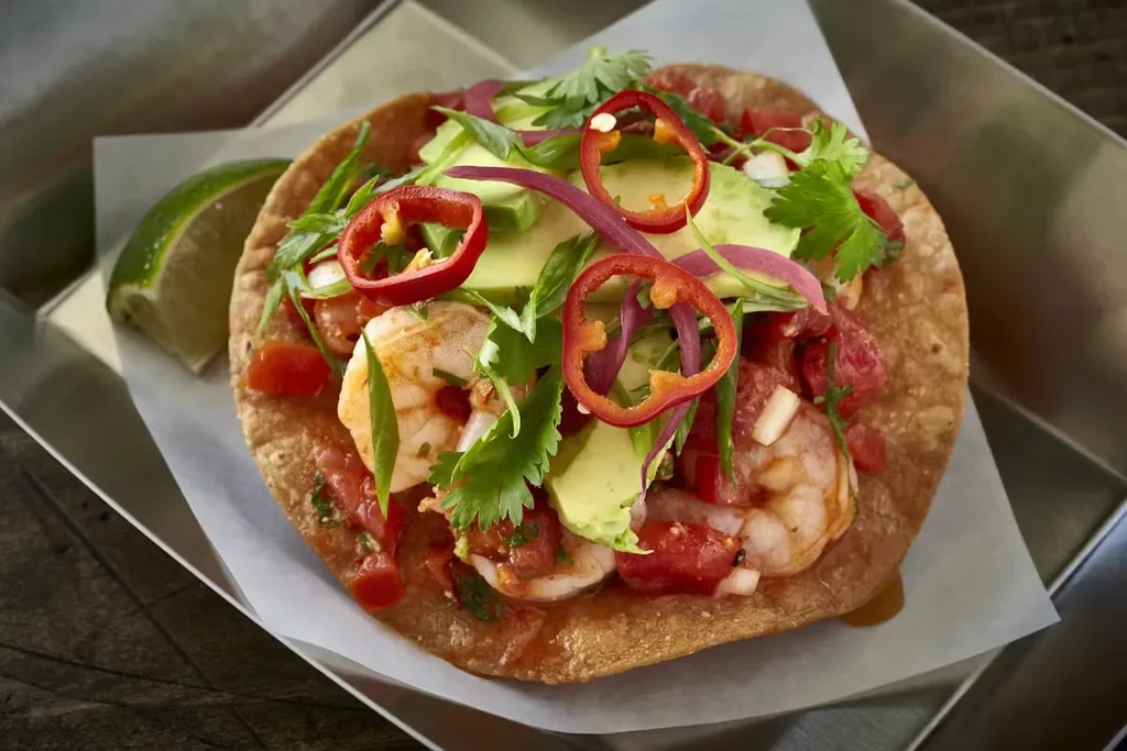 Shrimp tostada with avocado, tomato, onion, cilantro, and chili.