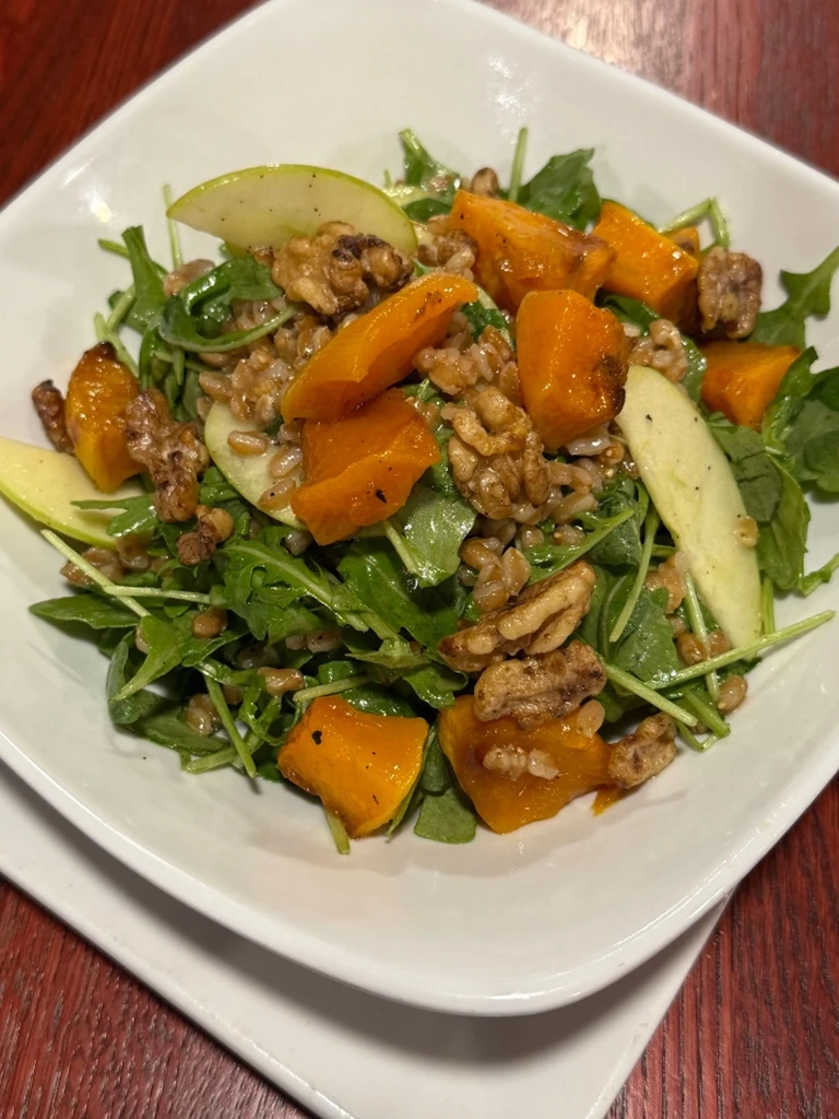 Salad with arugula, squash, walnuts, apple, and grains, overhead.