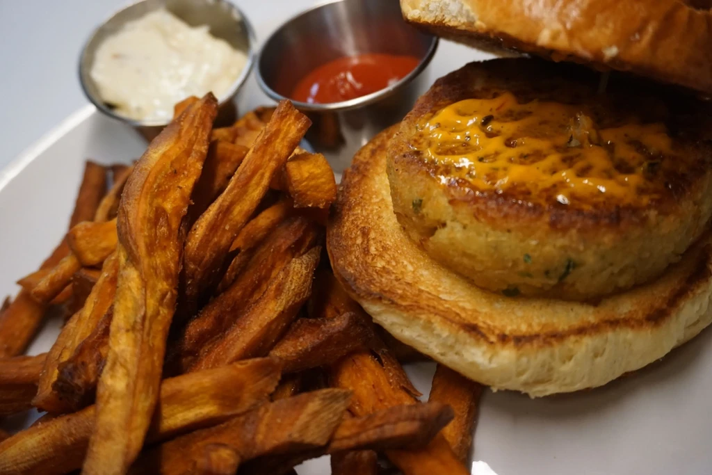 Crab cake sandwich with golden fries and two dipping sauces.